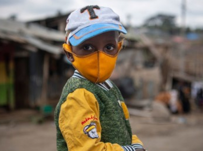 A young boy wears a face mask as he walks through Mathare, an informal settlement in Nairobi, Kenya. Photo credit: UNICEF/Alissa Everett