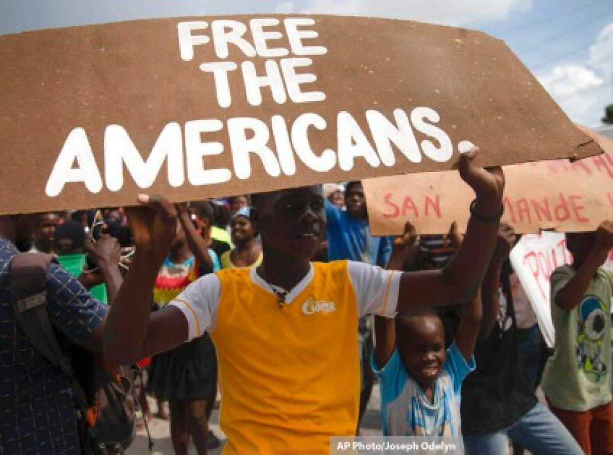 Protestors hold signs calling for the release of kidnapped missionaries, north of Port-au-Prince, Haiti, Oct. 19, 2021.
