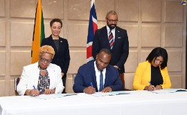 Minister of Foreign Affairs and Foreign Trade, Senator Hon. Kamina Johnson Smith (standing left) and Secretary of State for Foreign, Commonwealth and Development Affairs, United Kingdom (UK), the Rt. Hon. James Cleverly (standing right) observe the signing of a Memorandum of Understanding (MOU) between Jamaica and the British Council on co-operation in Science, Technology, Engineering, Arts and Mathematics (STEAM). (Photo by RUDRANATH FRASER of JIS)