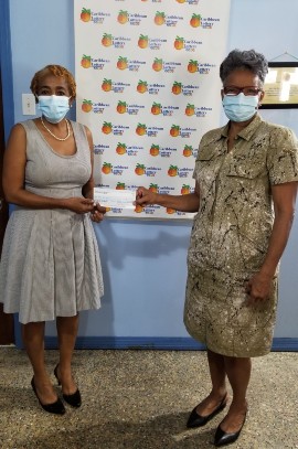 Ms. Paula Williams, Site Manager, Caribbean Lottery (left) presents a cheque to Radio Broadcaster and organizer of the Now You Know Breakfast Program, Ms. Valerie van Putten of SZV Radio.  The donation will assist students at the Prins Willem Alexander School with one meal each day during school hours.