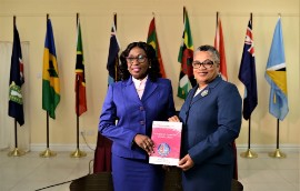 Dame Janice (left) receives a copy of the publication from by Madam Louise Esther Blenman (OECS Commission Photo)