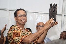 Ambassador David Comissiong holds up The Presidents Award, presented to him at the 20th anniversary of the St. Martin Book Fair, June 4, 2022. (© 2022 St Martin Book Fair photo.)