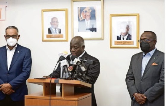 Prime Minister Phillip Davis (center) flanked by senior Cabinet ministers, speaking to reporters on his return from Rwanda