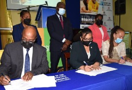 From left, seated: Commissioner of Corrections, Department of Correctional Services (DCS), Lieutenant Colonel (Ret.), Gary Rowe; Deputy Executive Chair, University of the Commonwealth Caribbean (UCC) Group, Geraldine Adams; and Executive Director, Stand up for Jamaica, Carla Gullotta signing the Memorandum of Understanding.