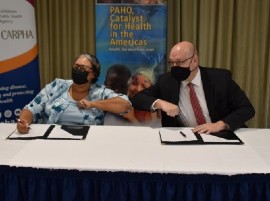 CARPHA Executive Director, Dr Joy St John and PAHO Sub-regional Program Director share an elbow bump after signing a Subsidiary Agreement to improve regional public health, including health security.