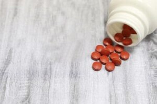 Pills and red knitted heart on woodeension, heart disease, blood pressure