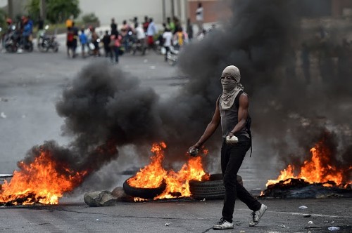 TOPSHOT - A demonstrator walks past next to barricades during clashes with Haitian police, in Port-au-Prince, on February 15, 2019, on the ninth day of protests against Haitian President Jovenel Moise and the misuse of the Petrocaribe fund. - Since February 7, at least seven people have died as Haiti has been plunged into political crisis, with everyday life paralyzed by protests and barricades in the largest towns. (Photo by HECTOR RETAMAL / AFP)        (Photo credit should read HECTOR RETAMAL/AFP via Getty Images)