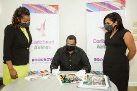 From left: Caribbean Airlines Loyalty Coordinator Gillian Samuel, Photographer Sanjiv Samoaroo signs prints of his work 'Hummingbird Mother with Babies' and Executive Manager Marketing and Loyalty, Alicia Cabrera.