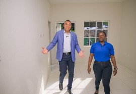 Prime Minister Andrew Holness (left), tours a New Social Housing Programme unit in Greendale district, Bull Bay, with recipient Jodian Bernard on Wednesday. (Photo credit: JIS)