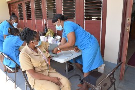 Community Health Aide from the Clarendon Health Department, Sharlene Carty (right) checks the blood pressure of Public Health Nurse from the Manchester Health Department, Shernett Kerr-Turner during the commemoration of World Cancer Day recently.