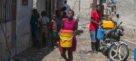 A woman in Port-au-Prince, Haiti, carries water she has bought from a local trader. (UNICEF/Odlyn Joseph)