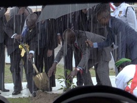Prime Minister of Trinidad and Tobago, Dr. Keith Rowley (right) along with his Bahamian colleague, Phillip Davis, plant a poui tree amidst pouring rain in Chaguaramas, to mark the 50th anniversary of CARICOM on Tuesday. (CMC photo)