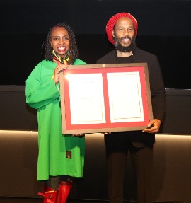 Jamaican-American Congresswoman Yvette Clarke presents a copy of the resolution to Ziggy Marley, son of Bob Marley, recognize the life and legacy of legendary reggae artist Robert ‘‘Bob’’ Nesta Marley . The presentation was made at a special screening of the BOB MARLEY: ONE LOVE film at the Motion Pictures Association in Washington, on Tuesday February 13. (Photo by Derrick Scott)