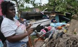 A woman stands among the ruins caused by Hurricane Melissa