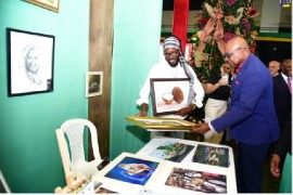 Tourism Minister Edmund Bartlett admiring a canvass painting by artist Delroy Milllwood at the opening of the Christmas in July trade show.