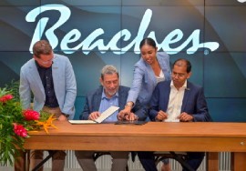 Prime Minister Dr. Ralph Gonsalves (center) about to sign agreement with the chief executive officer of Sandals Resorts International (SRI), Adam Stewart (standing) on Monday (API Photo)