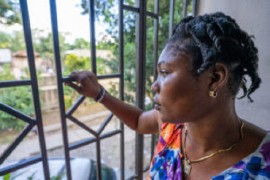 Mireille gazes through the protective bars at the GARR facility, reflecting on her journey back to Haiti. (IOM/Antoine Lemonnier)