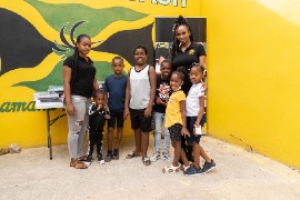 Keturah Hamilton (in full black) with parent and students who received educational products at Tredegar Park in St. Catherine parish Jamaica last August.