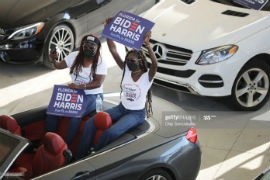 Wearing face masks and sitting in their cars to reduce the risk posed by the coronavirus, Caribbean American supporters, including Miramar Commissioner Alexandra Davis, (R), listen to Democratic presidential nominee Joe Biden deliver remarks during a drive-in voter mobilization event at Miramar Regional Park October 13, 2020 in Miramar, Florida. (Photo by Chip Somodevilla/Getty Images)