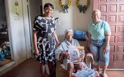 100-year-old Annie Johnson receives a hurricane kit from Chairwoman Edmonson, left, and Communities United Inc. Executive Director Hattie Willis.