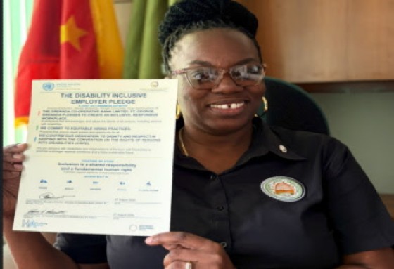 Ms. Nicola Philip, Executive Manager Human Resources, Grenada Co-operative Bank Limited, displays the Disability Inclusive Employer Pledge, signed by Managing Director Larry Lawrence.