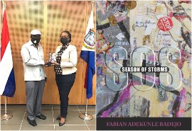 Prime Minister Silveria Jacobs (R), holds SOS: Season of Storms, the new poetry book presented by journalist, literary critic, author Fabian Adekunle Badejo, at the Government Administration Building, Philipsburg, St. Martin (9.8.21). (FAB courtesy photo.)