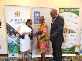 Programme Director, Planning Institute of Jamaica's (PIOJ) Vision 2030 Jamaica Secretariat, Peisha Bryan Lee, (left) and Dr Wayne Henry PIOJ Director General (right) demonstrate PIOJ's new Data 4 Development online monitoring platform to UNDP Resident Representative Denise E Antonio on her tablet. They were at the launch of the online platform. UNDP proudly supported with 13.5 million in seed funding. (PIOJ Photo).